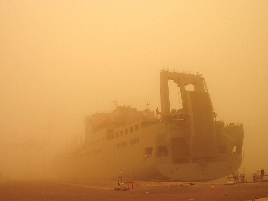 8. USNS Brittin (T-AKR 305) is a United
                            States Navy Military Sealift Command Large,
                            Medium-Speed Roll-on/Roll-off Ship (LMSR),
                            But This Windstorm Generates a Sandstorm
                            That Is So Huge It Significantly Blocks
                            (Filters) the Sun's Rays -- Casting a
                            Yellow-Orange Hue Everywhere -- and
                            Dramatically Obscures Much of the Docked
                            Ship, 2003, Port of Ash Shuaybah, Dawlat al
                            Kuwayt - State of Kuwait. Photo Credit:
                            Military Sealift Command: 2003 in Review
                            (http://www.msc.navy.mil/annualreport/2003/organization.htm)
                            and Sealift, May 2003: 'MSC ships, crews
                            deliver to inhospitable places'
                            (http://www.msc.navy.mil/sealift/2003/May/inhospitable.htm),
                            Military Sealift Command (MSC,
                            http://www.msc.navy.mil), United States Navy
                            (USN, http://www.navy.mil), United States
                            Department of Defense (DoD,
                            http://www.DefenseLink.mil or
                            http://www.dod.gov), Government of the
                            United States of America (USA).