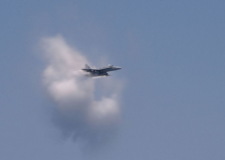 2. United States Navy F/A-18 Hornet Fighter Jet. July 26, 2003 Atlantic Ocean. Reaching the sound barrier, breaking the sound barrier: Flying at transonic speeds (flying transonically) -- speeds varying near and at the speed of sound (supersonic) -- speeds can generate impressive condensation clouds caused by the Prandtl-Glauert Singularity. For a scientific explanation, see Professor M. S. Cramer's Gallery of Fluid Mechanics, Prandtl-Glauert Singularity at <http://www.GalleryOfFluidMechanics.com/conden/pg_sing.htm>; and Foundations of Fluid Mechanics, Navier-Stokes Equations Potential Flows: Prandtl-Glauert Similarity Laws at <http://www.Navier-Stokes.net/nspfsim.htm>. Photo Credit: Photographer's Mate 2nd Class Danny Ewing Jr., Navy NewsStand - Eye on the Fleet Photo Gallery (http://www.news.navy.mil/view_photos.asp, 030726-N-4953E-081), United States Navy (USN, http://www.navy.mil), United States Department of Defense (DoD, http://www.DefenseLink.mil or http://www.dod.gov), Government of the United States of America (USA).