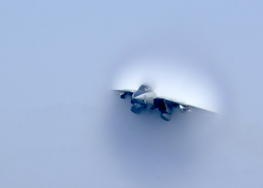 3. United States Navy F-14B Tomcat Fighter Jet. April 22, 2003, Mediterranean Sea. Reaching the sound barrier, breaking the sound barrier: Flying at transonic speeds (flying transonically) -- speeds varying near and at the speed of sound (supersonic) -- can generate impressive condensation clouds caused by the Prandtl-Glauert Singularity. For a scientific explanation, see Professor M. S. Cramer's Gallery of Fluid Mechanics, Prandtl-Glauert Singularity at <http://www.GalleryOfFluidMechanics.com/conden/pg_sing.htm>; and Foundations of Fluid Mechanics, Navier-Stokes Equations Potential Flows: Prandtl-Glauert Similarity Laws at <http://www.Navier-Stokes.net/nspfsim.htm>. Photo Credit: Photographer's Mate Airman Justin S. Osborne, Navy NewsStand - Eye on the Fleet Photo Gallery (http://www.news.navy.mil/view_photos.asp, 030422-N-0382O-588), United States Navy (USN, http://www.navy.mil), United States Department of Defense (DoD, http://www.DefenseLink.mil or http://www.dod.gov), Government of the United States of America (USA).