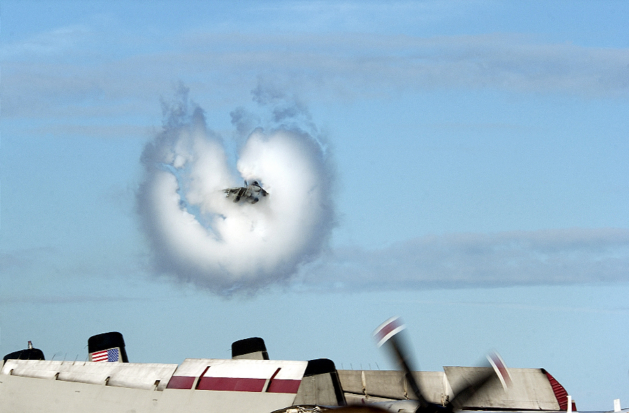 5. An F-14 Tomcat Fighter Jet Assigned to the 'Jolly Rogers' of Fighter Squadron One Zero Three (VF-103), September 26, 2002, United States Navy. Reaching the sound barrier, breaking the sound barrier: Flying at transonic speeds (flying transonically) -- speeds varying near and at the speed of sound (supersonic) -- can generate impressive condensation clouds caused by the Prandtl-Glauert Singularity. For a scientific explanation, see Professor M. S. Cramer's Gallery of Fluid Mechanics, Prandtl-Glauert Singularity at <http://www.GalleryOfFluidMechanics.com/conden/pg_sing.htm>; and Foundations of Fluid Mechanics, Navier-Stokes Equations Potential Flows: Prandtl-Glauert Similarity Laws at <http://www.Navier-Stokes.net/nspfsim.htm>. Photo Credit: Journalist 2nd Class David Valdez, Navy NewsStand - Eye on the Fleet Photo Gallery (http://www.news.navy.mil/view_photos.asp, 020926-N-2781V-170), United States Navy (USN, http://www.navy.mil), United States Department of Defense (DoD, http://www.DefenseLink.mil or http://www.dod.gov), Government of the United States of America (USA).