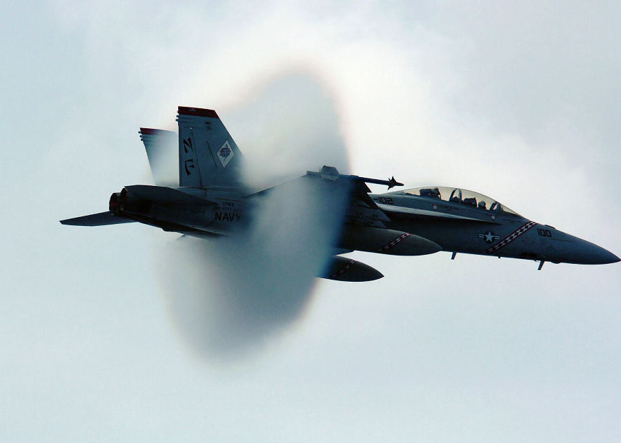 12. An F/A-18F Super Hornet Fighter Assigned to the 'Diamondbacks' of Strike Fighter Squadron One Zero Two (VFA-102). July 27, 2005, USS Kitty Hawk (CV 63), United States Navy in the Philippine Sea. Reaching the sound barrier, breaking the sound barrier: Flying at transonic speeds (flying transonically) -- speeds varying near and at the speed of sound (supersonic) -- can generate impressive condensation clouds caused by the Prandtl-Glauert Singularity. For a scientific explanation, see Professor M. S. Cramer's Gallery of Fluid Mechanics, Prandtl-Glauert Singularity at <http://www.GalleryOfFluidMechanics.com/conden/pg_sing.htm>; and Foundations of Fluid Mechanics, Navier-Stokes Equations Potential Flows: Prandtl-Glauert Similarity Laws at <http://www.Navier-Stokes.net/nspfsim.htm>. Photo Credit: Photographer's Mate 3rd Class Jonathan Chandler, Navy NewsStand - Eye on the Fleet Photo Gallery (http://www.news.navy.mil/view_photos.asp, 050727-N-3488C-051), United States Navy (USN, http://www.navy.mil), United States Department of Defense (DoD, http://www.DefenseLink.mil or http://www.dod.gov), Government of the United States of America (USA).