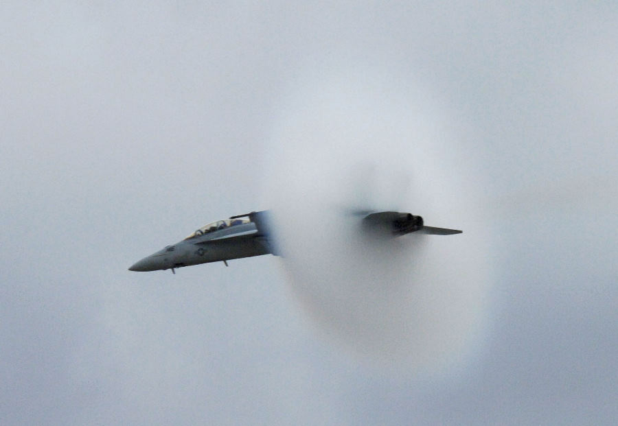 5. An F-14A Tomcat Fighter Jet, January 31, 1987, United States Navy. Reaching the sound barrier, breaking the sound barrier: Flying at transonic speeds (flying transonically) -- speeds varying near and at the speed of sound (supersonic) -- can generate impressive condensation clouds caused by the Prandtl-Glauert Singularity. For a scientific explanation, see Professor M. S. Cramer's Gallery of Fluid Mechanics, Prandtl-Glauert Singularity at <http://www.GalleryOfFluidMechanics.com/conden/pg_sing.htm>; and Foundations of Fluid Mechanics, Navier-Stokes Equations Potential Flows: Prandtl-Glauert Similarity Laws at <http://www.Navier-Stokes.net/nspfsim.htm>. Photo Credit: Photographer's Mate 2nd Class Johnson, Defense Visual Information Center (DVIC, http://www.DoDMedia.osd.mil, DNSC8711321) and United States Navy (USN, http://www.navy.mil), United States Department of Defense (DoD, http://www.DefenseLink.mil or http://www.dod.gov), Government of the United States of America (USA).